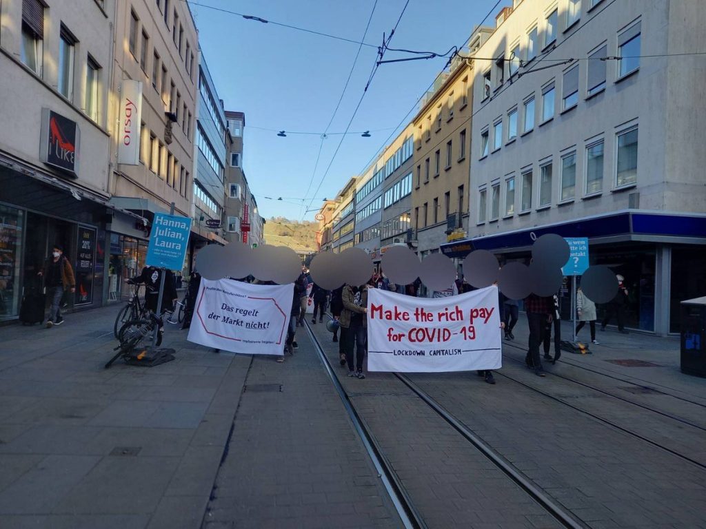 Frontblock der lockdown capitalism Demo für die Einführung einer sofortigen Vermögenssteuer in der Kaiserstraße. Auf den zwei Fronttranspis steht: "Das regelt der Markt nicht!" und "Make the rich pay for COVID-19 - lockdown capitalism"